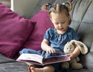 2 year old girl reading with bunny